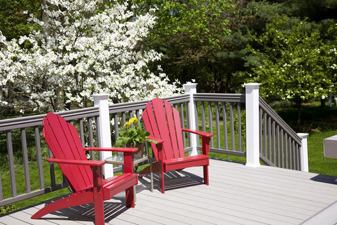 Dogwood tree behind two red adriondack chairs on a gray and white porch 