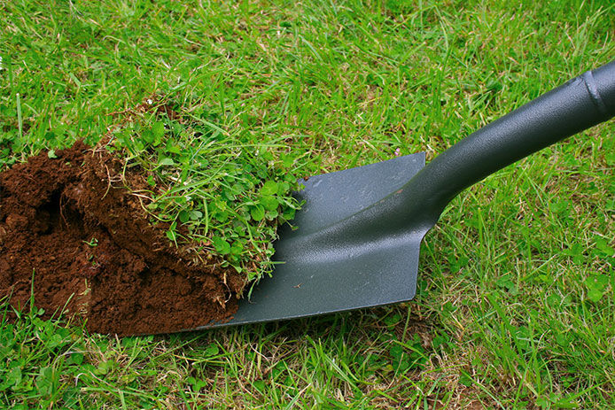 A person digging up grass with a shovel 