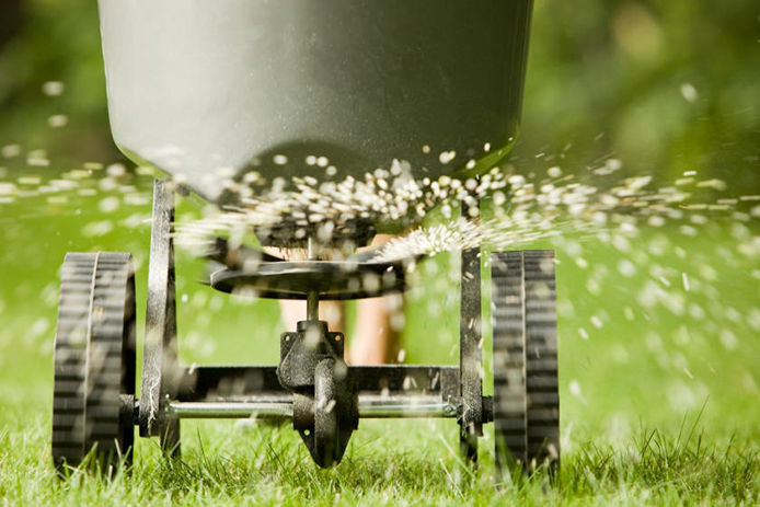 spreader fertilizing a green lawn 
