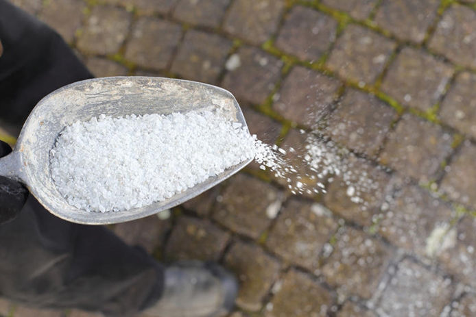 Salt being poured onto a brick walk way 