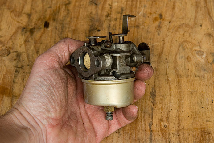 Hand holding a small engine carburetor