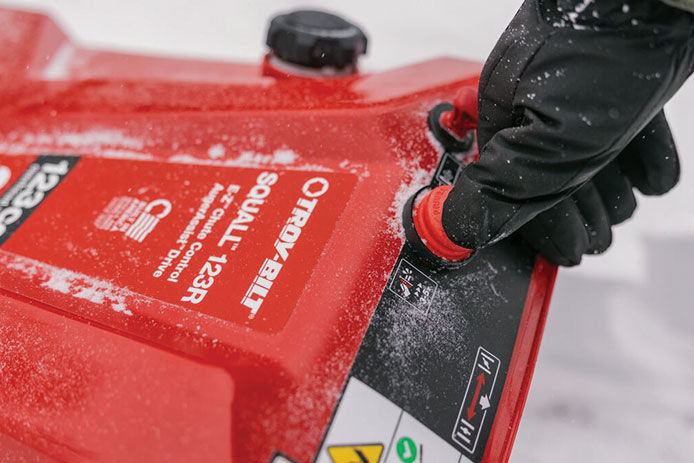 Person pushing the primer on a snow blower