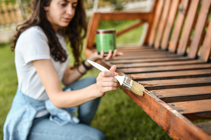 woman staining outdoor furniture