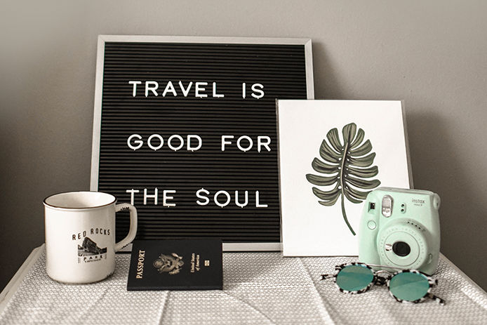 Travel sign, Red Rocks mug, polaroid camera, sunglesses, and passport