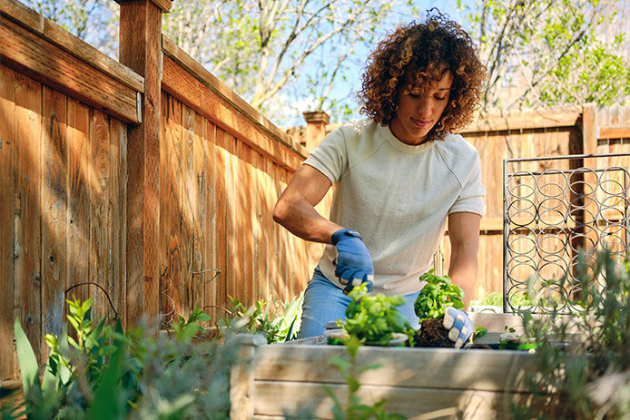 Woman in her backyard tending to her raised garden beds