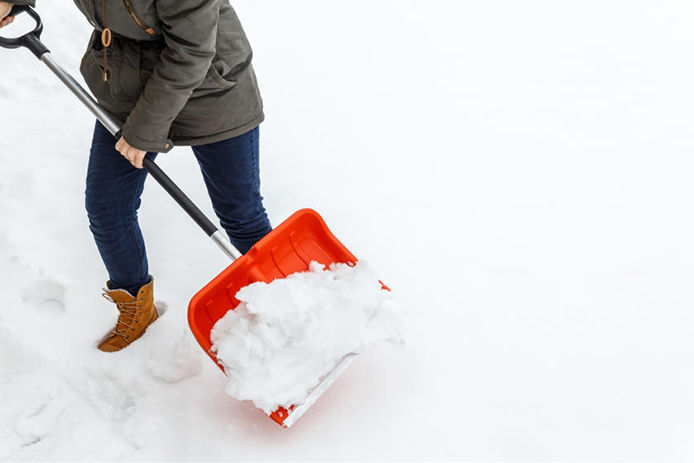 Woman shoveling snow with a red shovel 