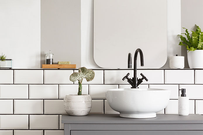 White sink & black faucet in a white subway tiled bathroom