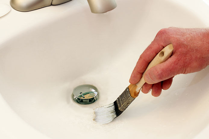 Using a paint brush to apply in bathroom sink