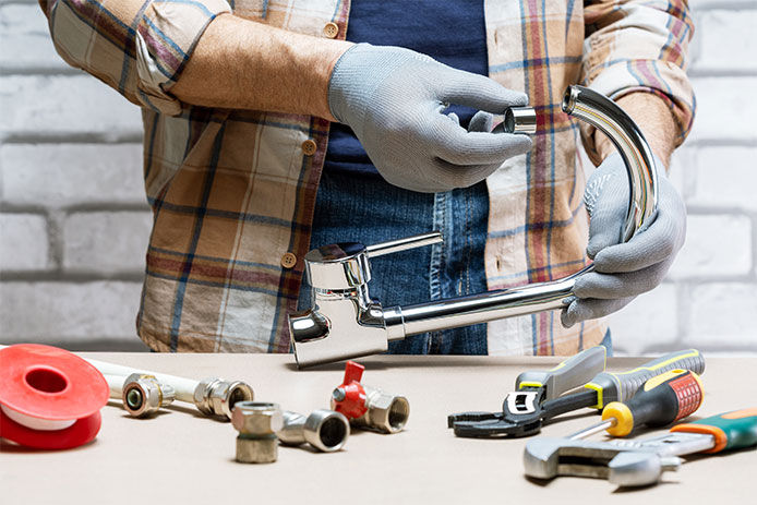 Man has a faucet completely taken apart on a countertop