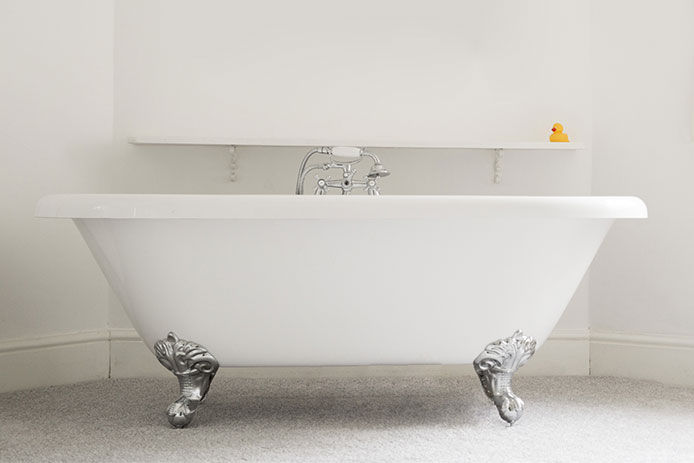 A white ceramic bathrub in an all white bathroom