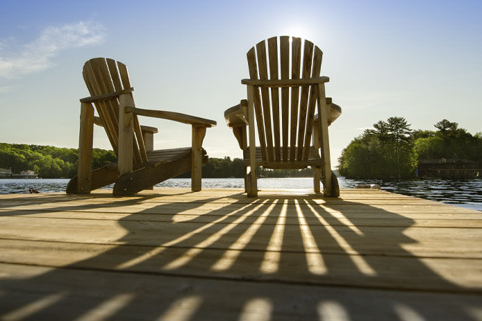 Two wooden chairs sitting on a dock
