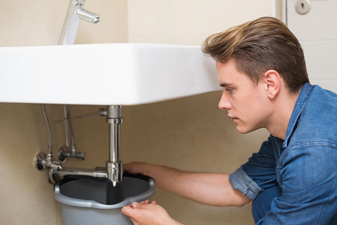 A man checking a sink for leaks