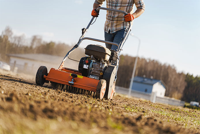 Man using aerator machine to scarification and aeration of lawn or meadow