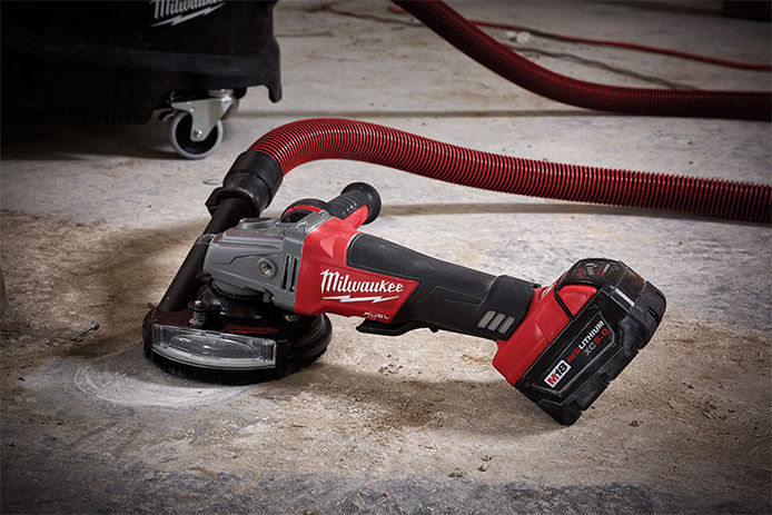 Milwaukee M18 cordless angle grinder hooked up to a vacuum suction intank to collect dusk while working 