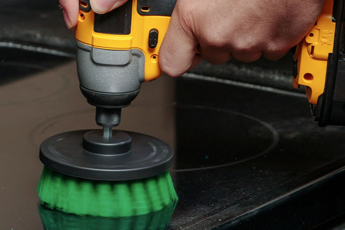 using a green DrillBrush on a kitchen appliance