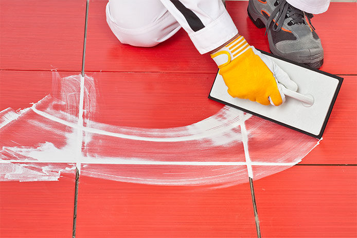 Applying new grout between red tiles