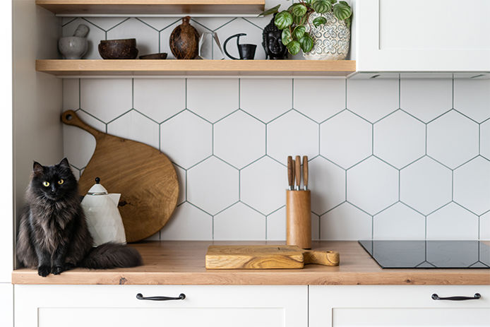 White hexagon backsplash tile with wood countertops and white cabinetry