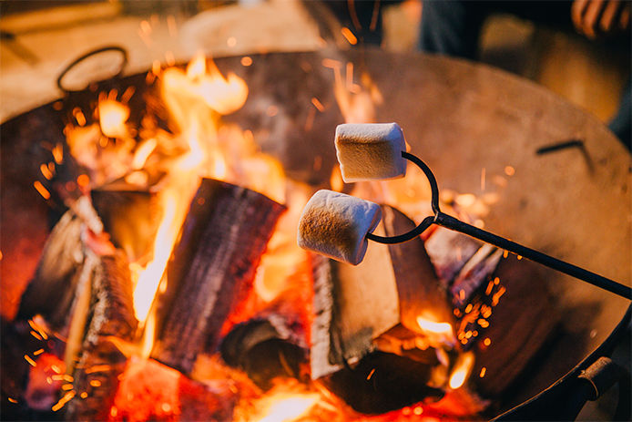 A close up of marshmallow roasting over a backyard firepit