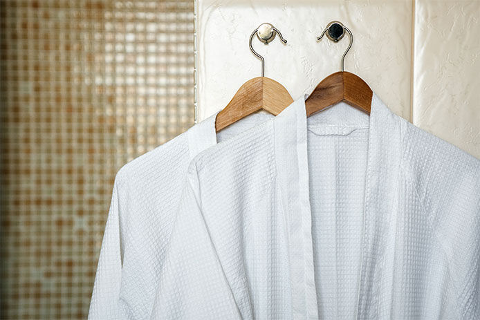 Two bathrobes hanging up in a bathroom