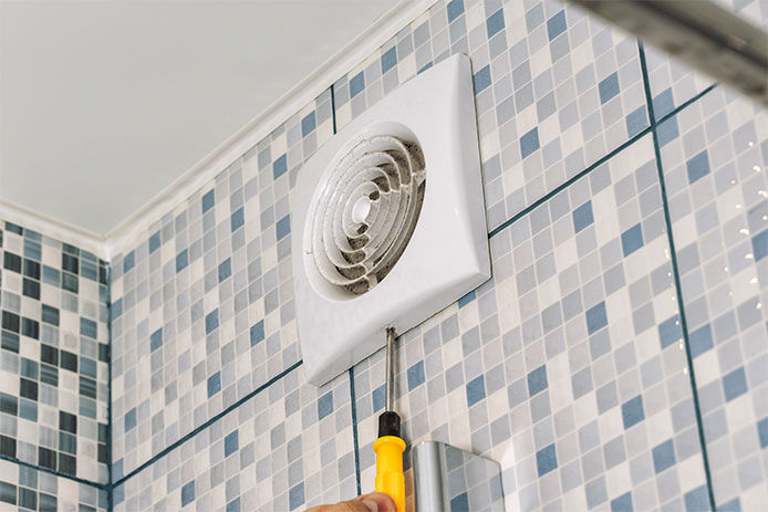 A person installing a bathroom fan