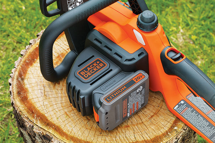 Chainsaw laying on a tree stump featuring the battery attached for power