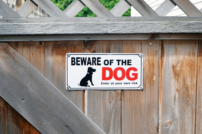 A sign that says "Beware of the dog" posted on a fence