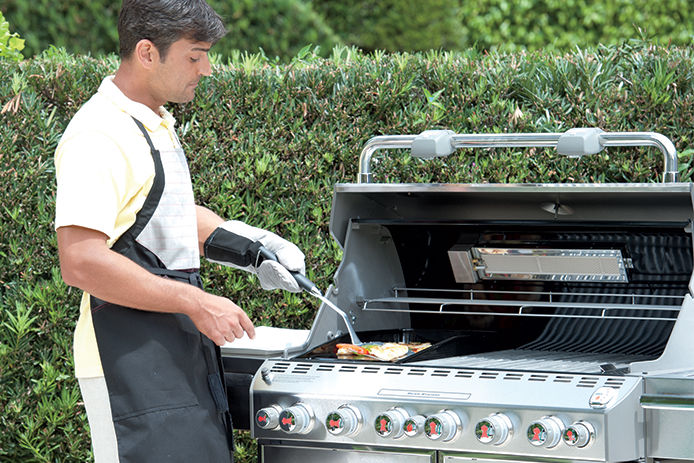 Adult man cleaning a Broil King propane grill