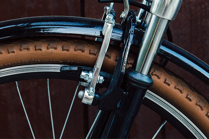 Close-up image of the front tire on a black bike with tan tires. The tire has a smooth, slick surface with a subtle tread pattern in the center. The tire appears to be well-maintained and fully inflated. 