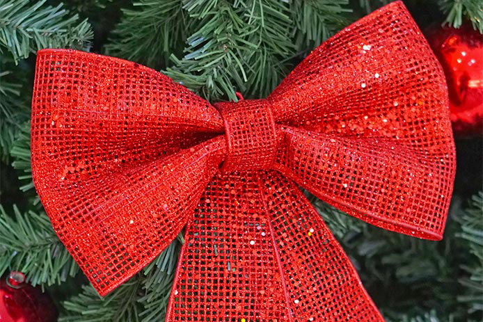 A red mesh bow hanging on a Christmas tree