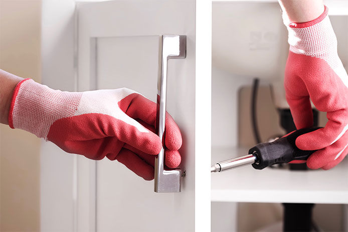 A person wearing pink work gloves while changing the hardware on a bathroom cabinet