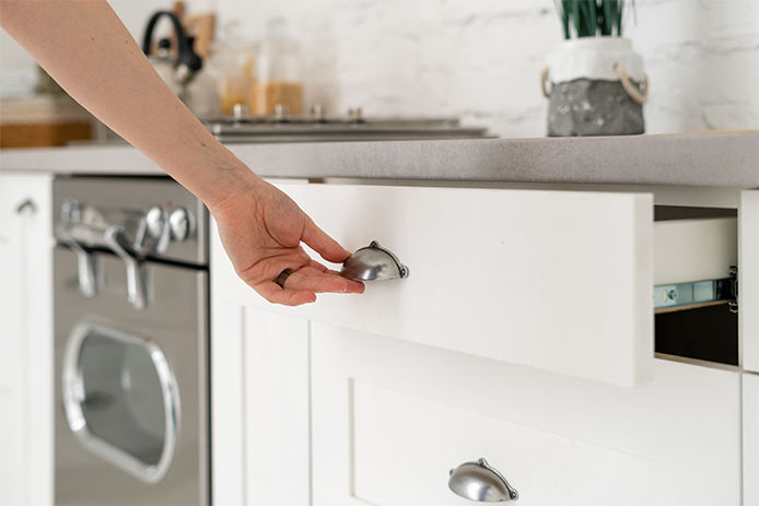 Woman pulling kitchen drawer out featuring cabinet pull