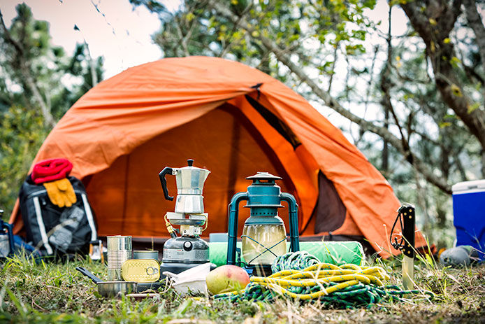 Camping gear all laid out in  the grass in front of an orange tent