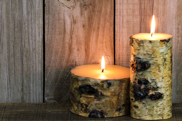 Two lit candles that look like small logs of wood