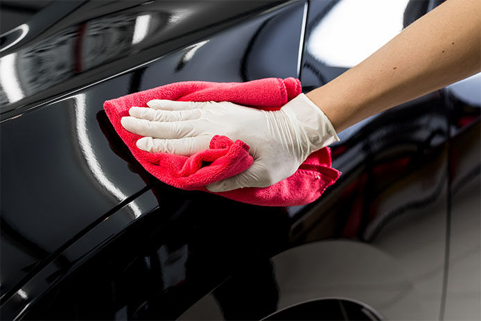 Man drying a car with a red microfiber towel