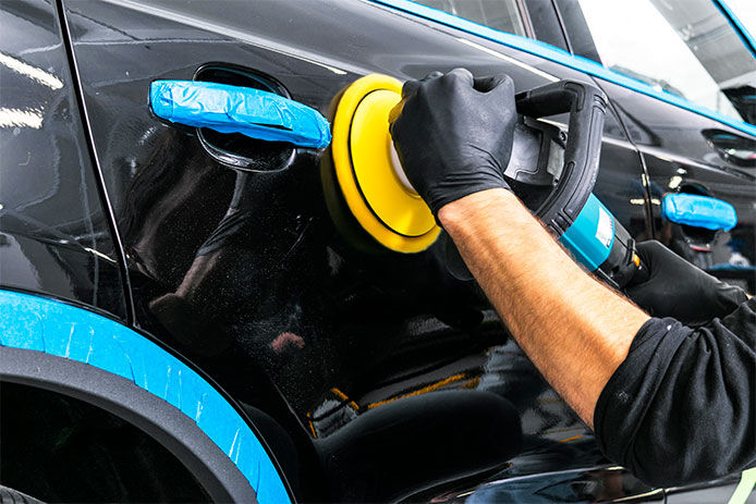 A man waxing a car with a power waxer