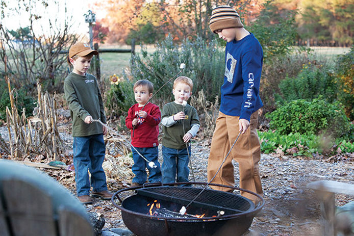 Four boys roasting marshmallows wearing Carhartt clothing