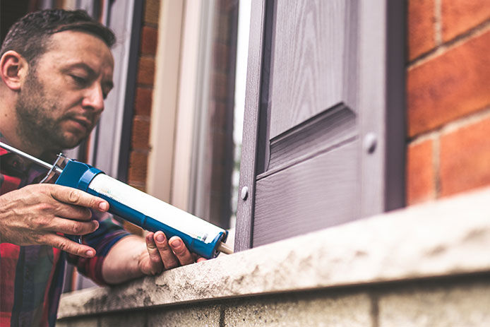 A man caulking up a window 