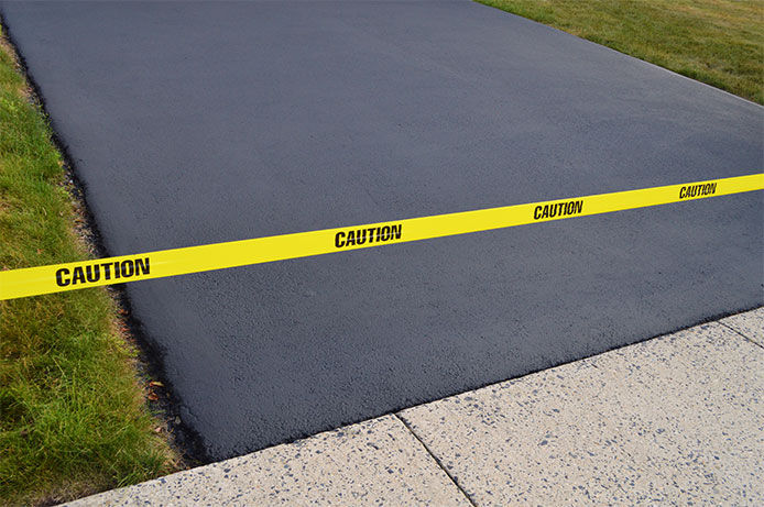 Caution tape at the end of an asphalt driveway