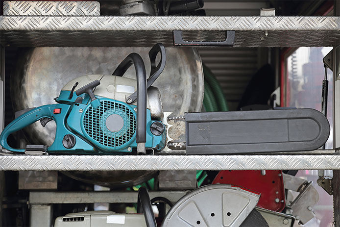 Chainsaw stored on a metal shelf with safety guard on the chain