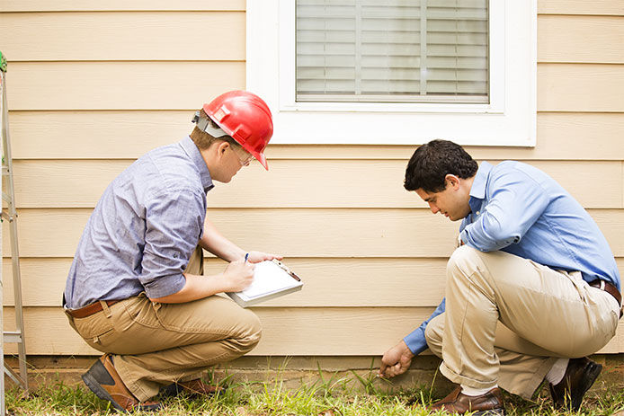 Two men checking a house foundation