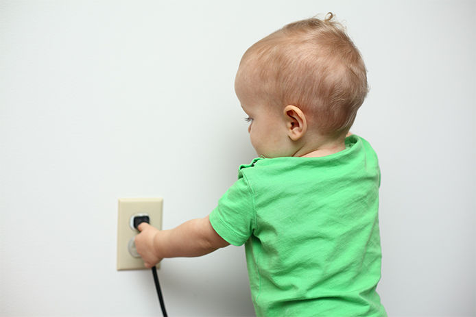 Baby trying to pull a cord from wall outlet