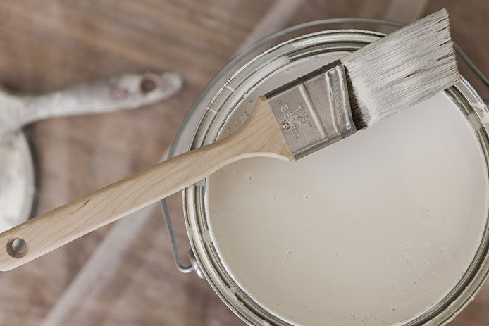 Paint brush laying on top of bucket of paint