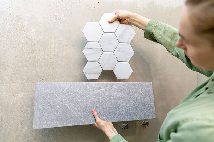 Woman holding up two different tiles trying to decide which to pick
