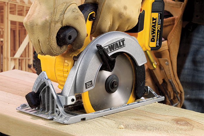 A close up image of a DEWALT circular saw being used to cut into a piece of lumber on a construction site