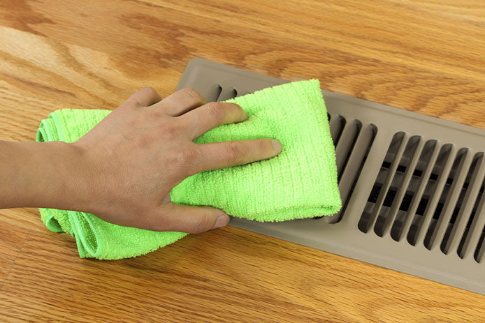 A person cleaning an air vent