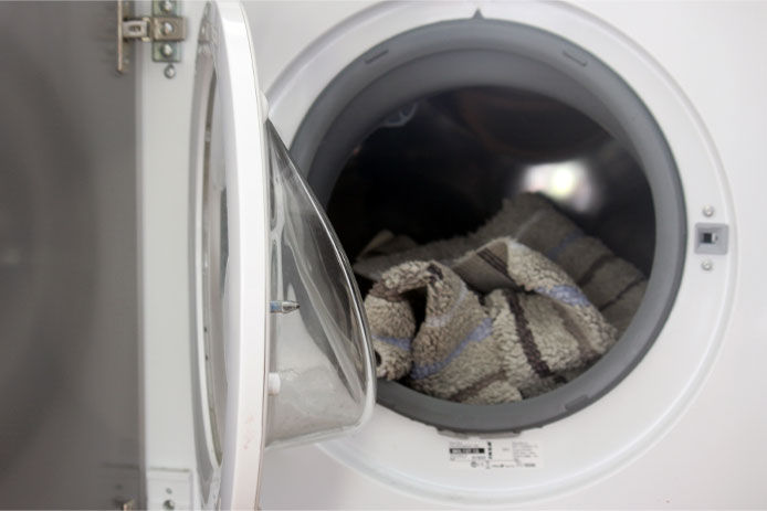 Front view of washing machine with a bathmat inside and door open