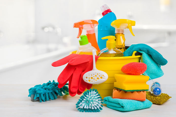 Bucket with chemical products on table over blurred bathroom background