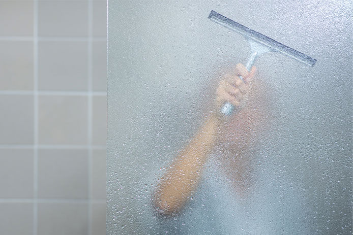 Woman taking a long hot shower washing her hair in a modern design bathroom