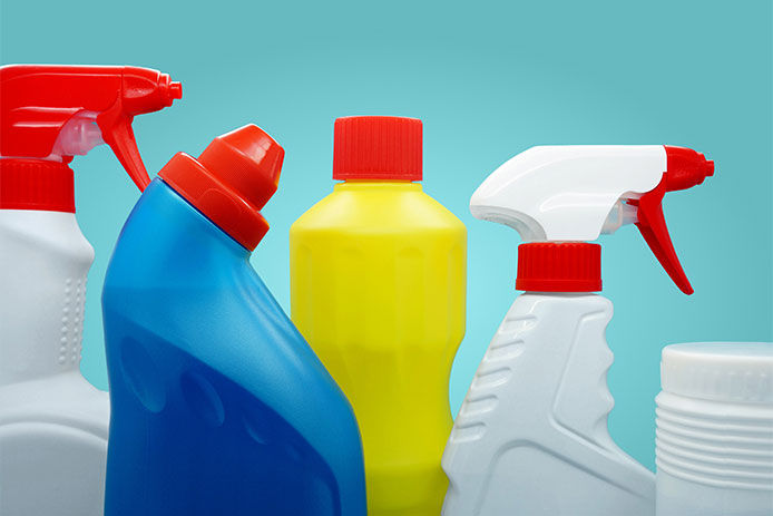 A close up image of a variety of cleaning spray bottles on a blue background