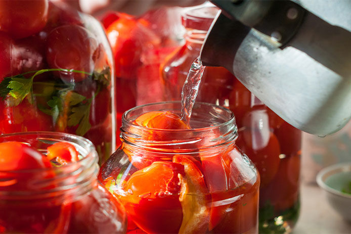 Pouring hot water into jar with fruit